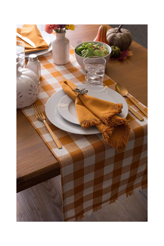 Fall table set for a dinner party featuring an orange and white checkered table runner. 