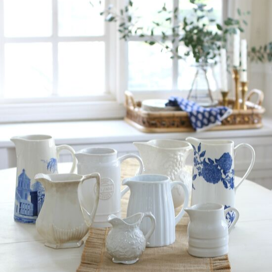 Collecting vintage pitchers in varying shades and shapes arranged on a dining table with a linen runner. 