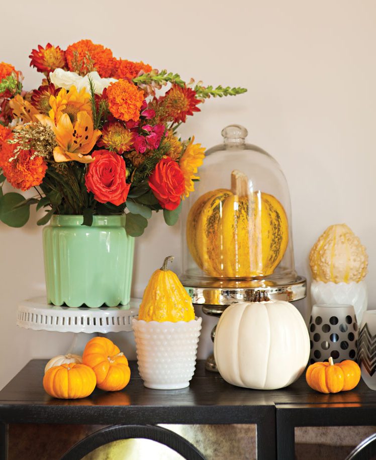 Black sideboard adorned with florals and various vases and gourds. 