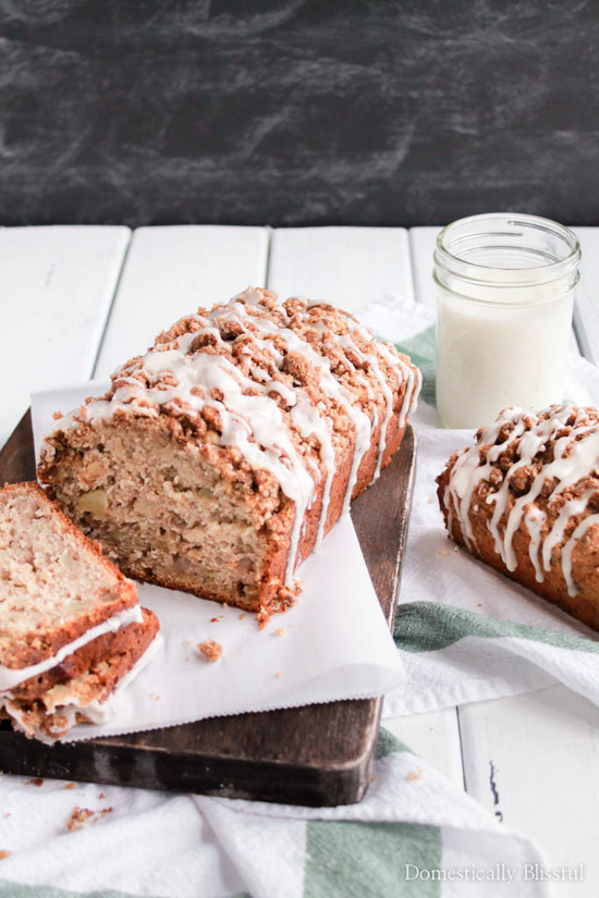 Fresh baked bread with a drizzled topping arranged on a cutting board next to a mason jar full of milk. 