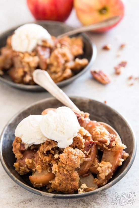 Two industrial looking bowls filled with generous portions of dessert and served with silver spoons and topped with ice cream. 