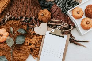 Cozy fall textiles surrounded by crafted pumpkins, eucalyptus sprigs and fall to-to lists.