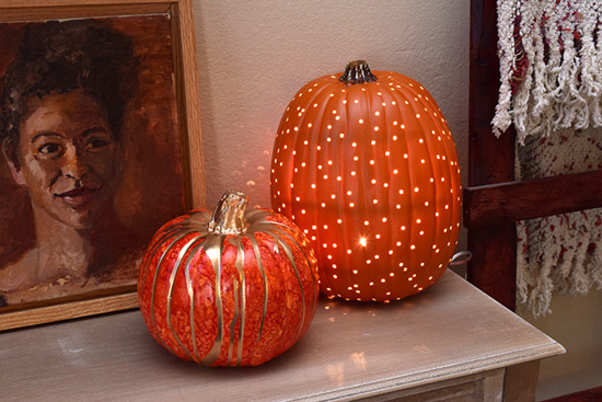 Two decorative pumpkins on a mantle next to a framed portrait. 