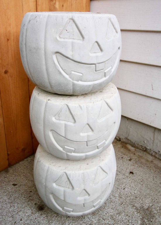 Set of 3 stacked identical cement pots in the shape of a halloween jack-o-lantern. 