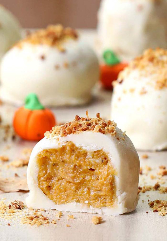 Pumpkin cheesecake balls arranged with small candy pumpkins. 