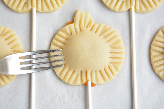 Cake pops in the shape of a pumpkin, showing a fork used to close the edges and create texture.