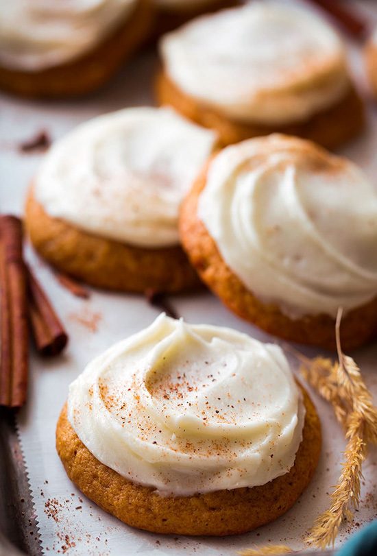 Pumpkin cookies on a cookie sheet and topped with cream cheese frosting.