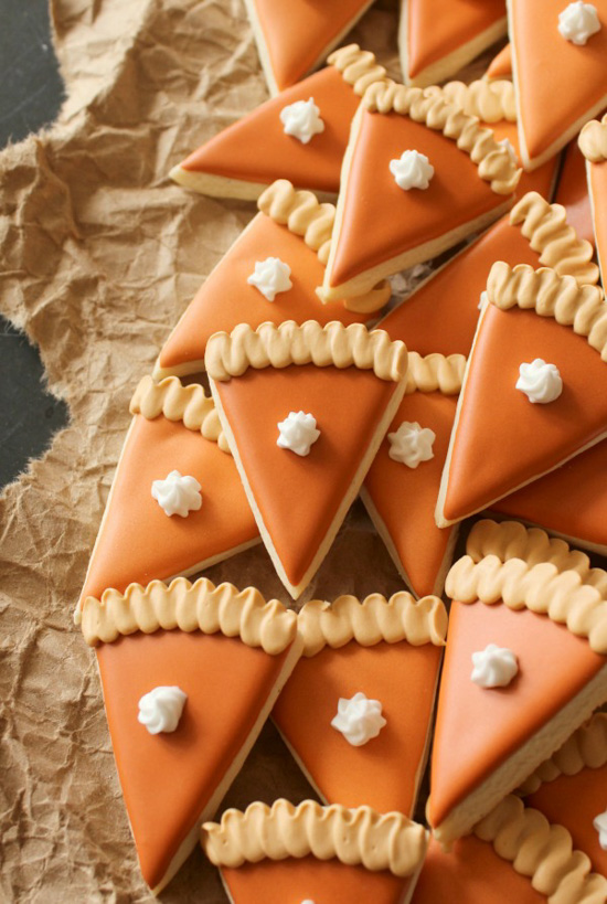 Beautifully designed sugar cookies in the shape of individual slices of pumpkin pie.