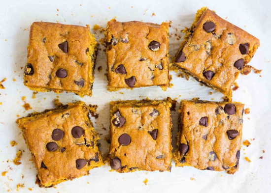 Six pumpkin, chocolate chip brownie squares viewed from above.