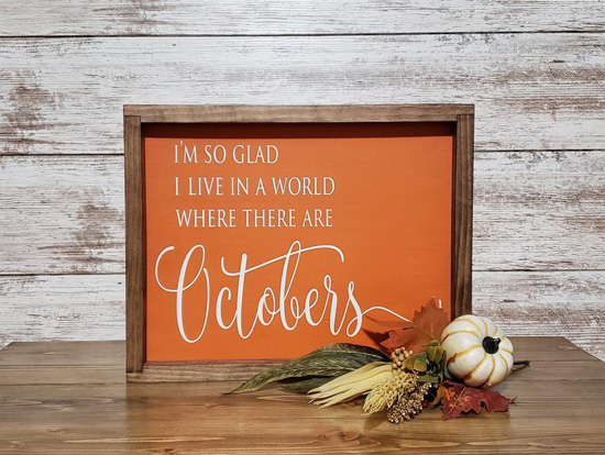 Rustic, farmhouse sign, wood frame and orange inlay that says, 'I'm so glad I live in a world where there are Octobers'. 