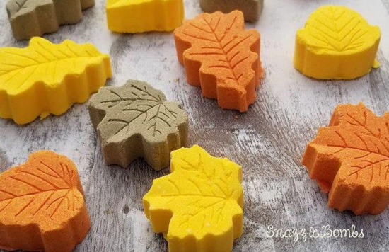 Small bath bombs in a variety of leaf shapes in shades of orange, yellow and brown. 