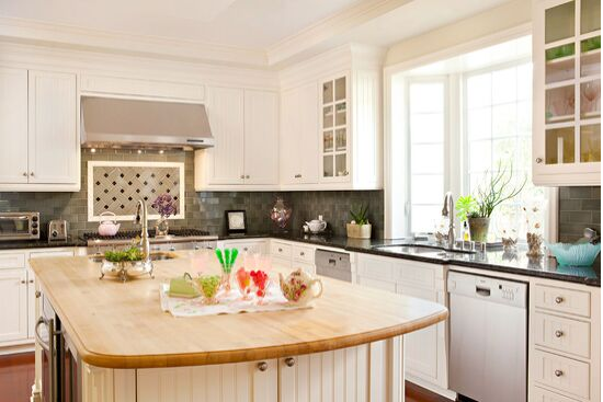 Open airy white kitchen with English Country Style and butcher block top island. 