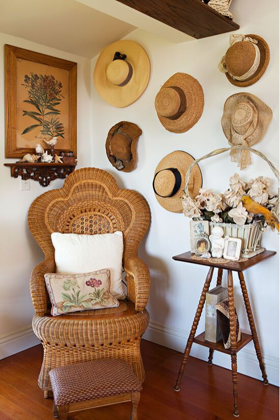 Vintage rattan peacock style chair and an accent wall covered in sun hats. 