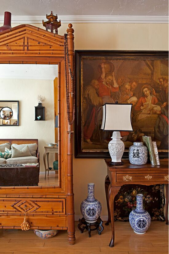 Mirrored armoire surrounded by oriental white and cobalt blue porcelain vases and a lamp. 