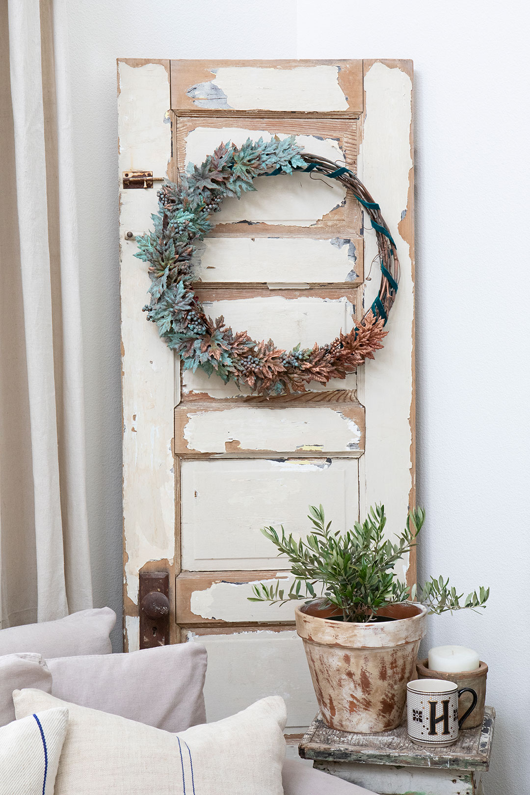 DIY copper patina wreath hung on a white door with chipping paint
