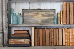 Bookshelves filled with art, aqua colored glass bottles and vintage books.