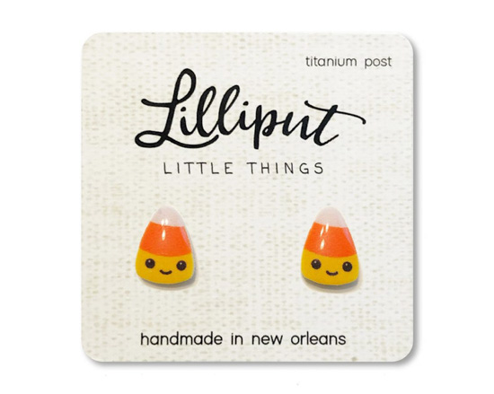 Miniature candy corn earrings with smiley faces, posted on a small cardboard business card. 