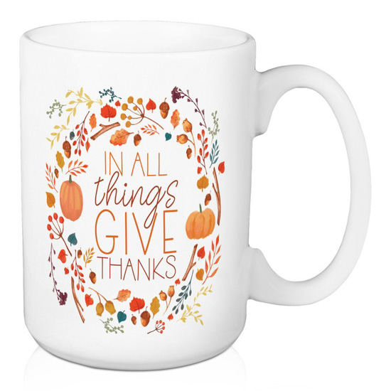 White porcelain mug with "in all things give thanks" written and encircled by fall foliage.