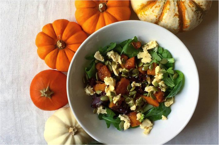 Fall Squash Salad with Maple Wine Vinaigrette in a white bowl surrounded by mini pumpkins