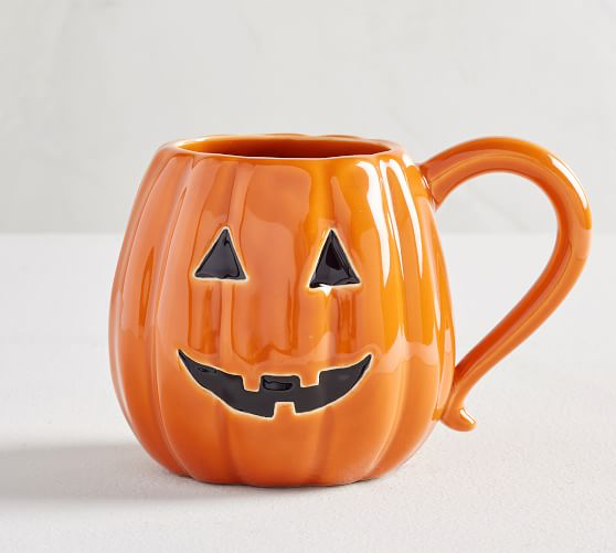 Orange ceramic mug designed to look like a pumpkin with jack-o-lantern face on one side. 