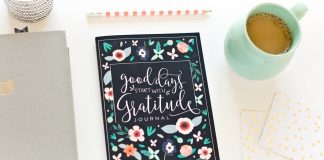 Gratitude journal placed next to a pencil, coffee mug, and notebooks.