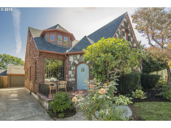 Storybook Cottage front elevation with charming roof lines and a light blue front door. 