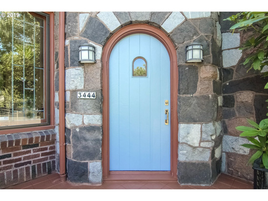 Stone covered front cottage entryway with a rounded light blue front door. 