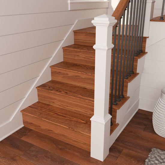 White and metal banister and the bottom portion of a staircase, displaying new wooden stair risers stained to match the wooden floors of the home.