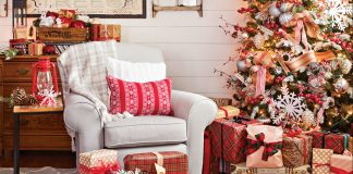 A cozy light colored armchair sat next to a sparkly lit Christmas tree surrounded by gifts.