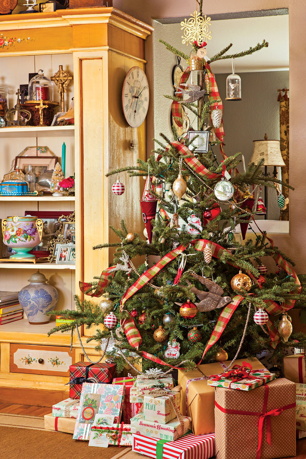Charlie Brown tree style with sparse branches but tons of character with ribbon and ornaments and present stacked around the bottom.
