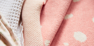 Layered blankets in various shades of cream and pink.