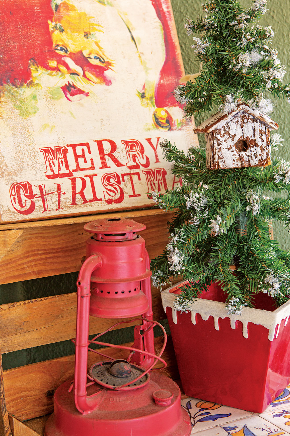 An antique piece of Santa art paired with a faux-flocked tree and a red antique lantern