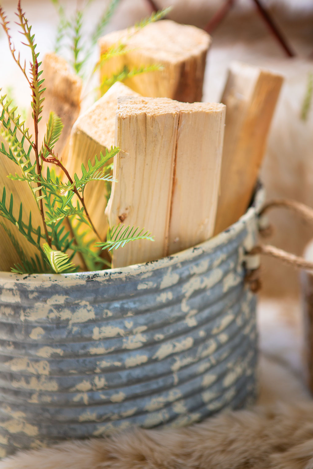 Stored firewood logs in a distressed, galvanized bucket. 