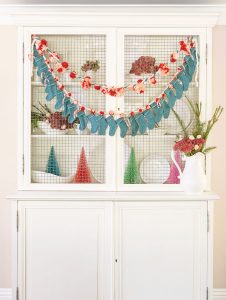 Teal and pink Christmas advent calendar made out of mini stockings, pink pom poms, and silver bells