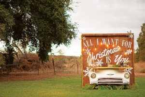 Barnyard bar set up with a large wooden backdrop attached to a vintage car front turned into a bar top.