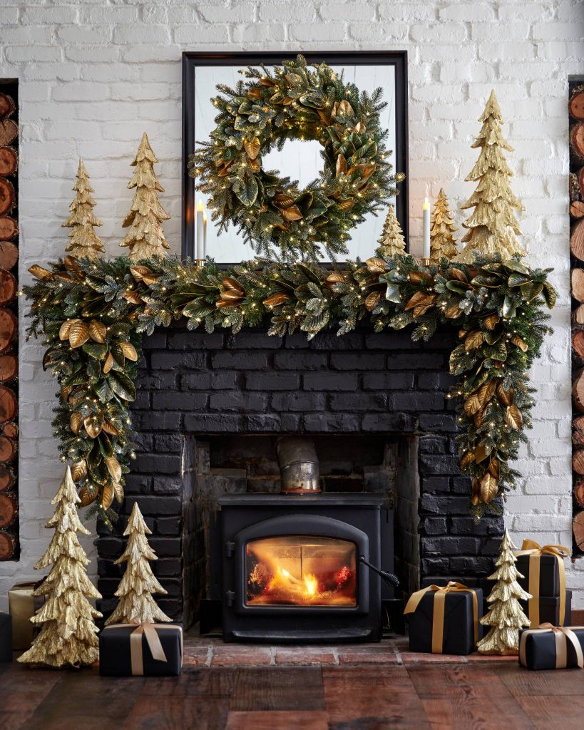 a black fireplace with gold wood trees on the mantel and hearth and a generous gilded Magnolia swag on the mantel. 