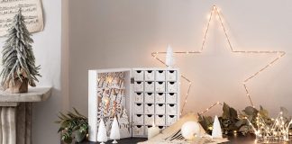 Winter wonderland display in white and bright twinkle lights displaying a white wooden box with advent drawers inside.