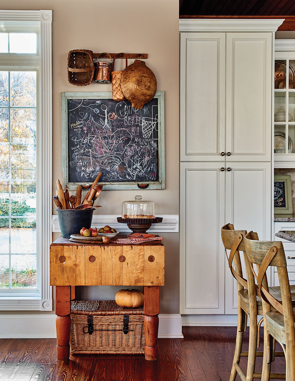 Antique butcher block in the kitchen surrounded by vintage baskets and kitchen tools and a chalkboard converted from an old window screen. 