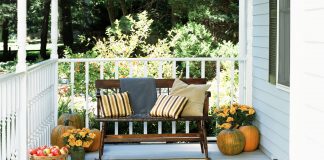 fall porch with vintage wooden bench, striped pillows in fall colors and pumpkins and apples in a basket
