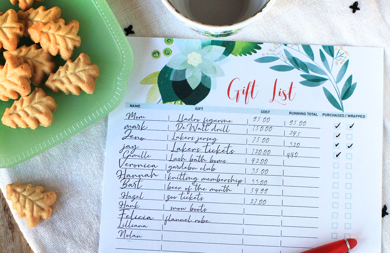 a christmas gift list worksheet next to a teacup and tree-shaped shortbread cookies