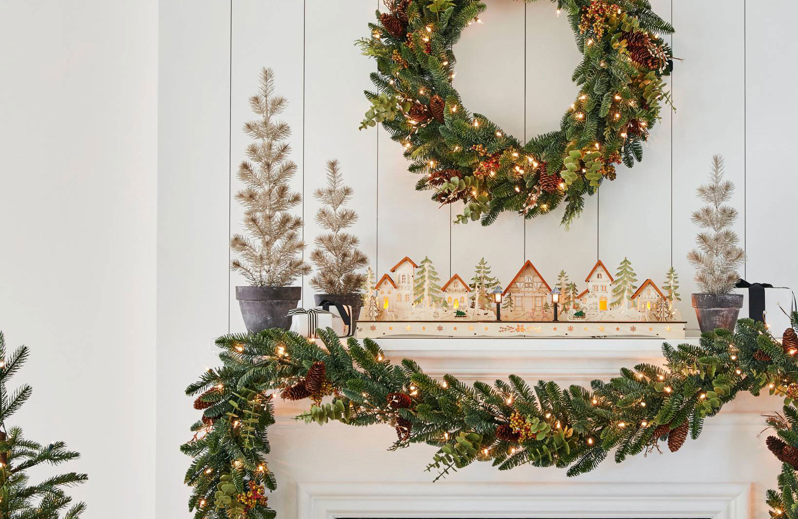 christmas mantel with garland and wooden christmas village