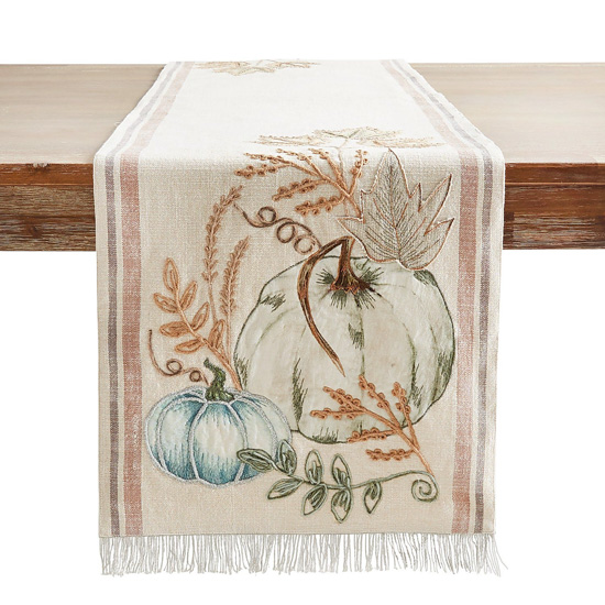 Wooden table featuring a cottage style thanksgiving table runner with a fringed edge. 