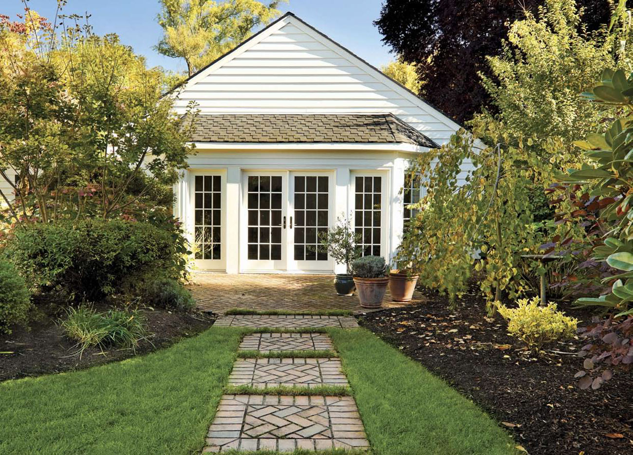 Custom brick pavers create a path through the garden toward a back house. 