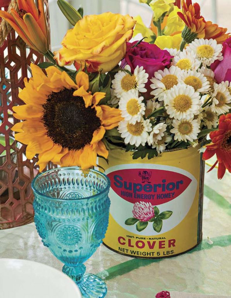 Blue glass goblet and a vintage can filled with fresh flowers.