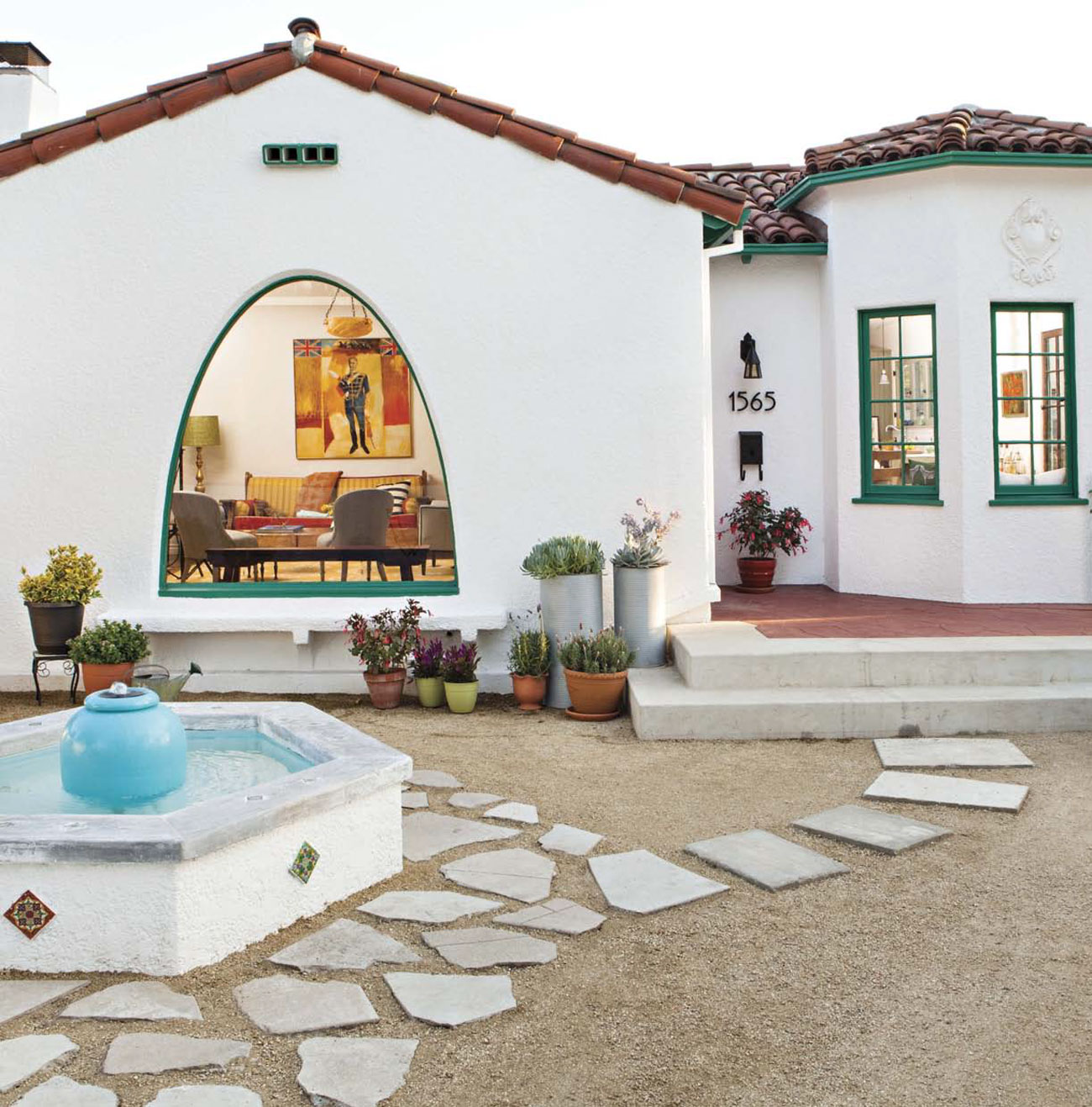 Front yard view of a Spanish bungalow with stone walkway and a fountain feature. 