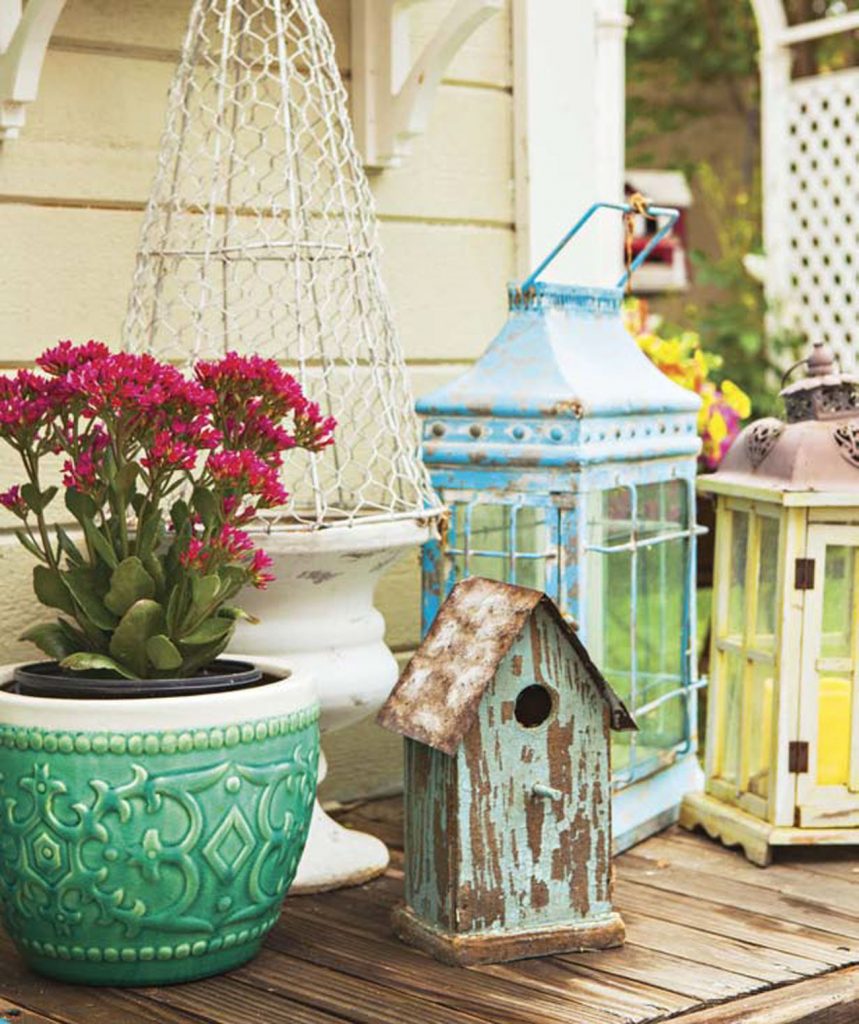 An outdoor collection of lanterns and birdhouses with colorfully distressed finishes. 