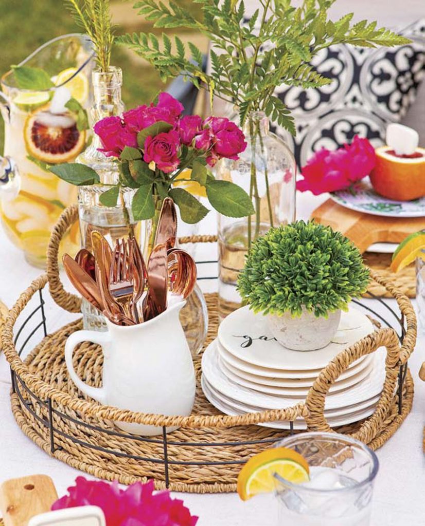 Woven tray used as a centerpiece with fresh flowers, small plates, vases and cutlery. 