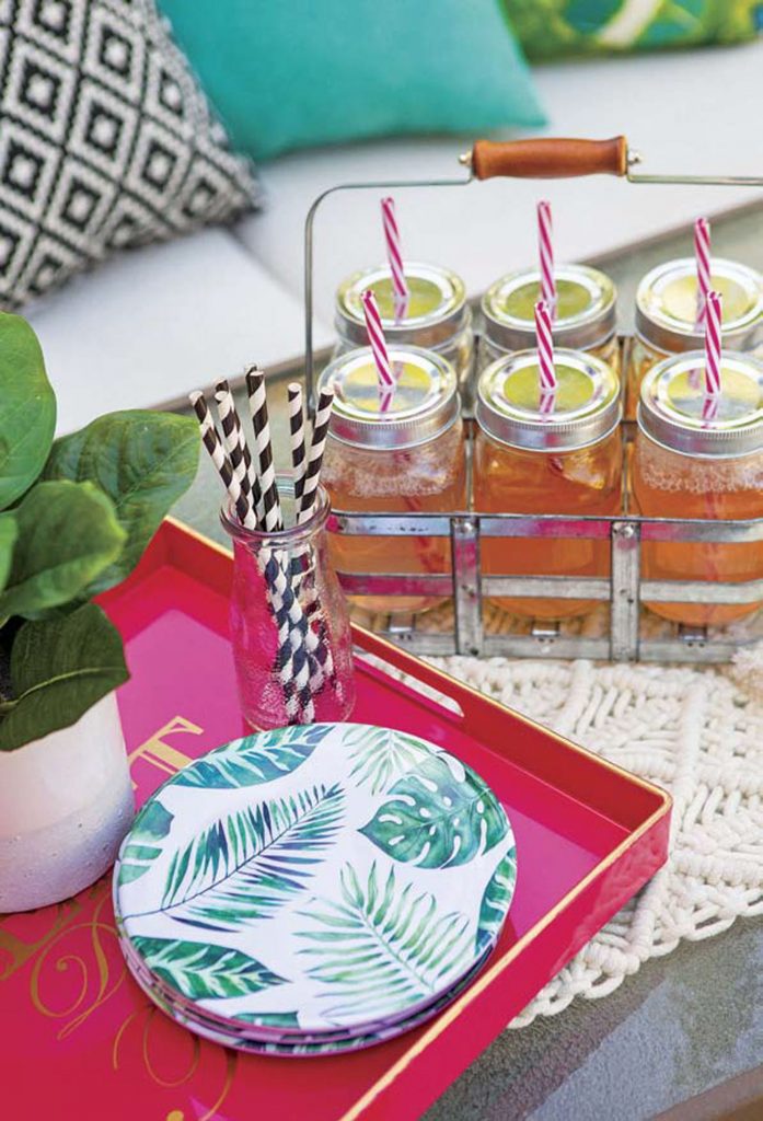 Bright colorful trays and mason jars with cocktails and striped straws loaded into a vintage-style beverage caddie. 