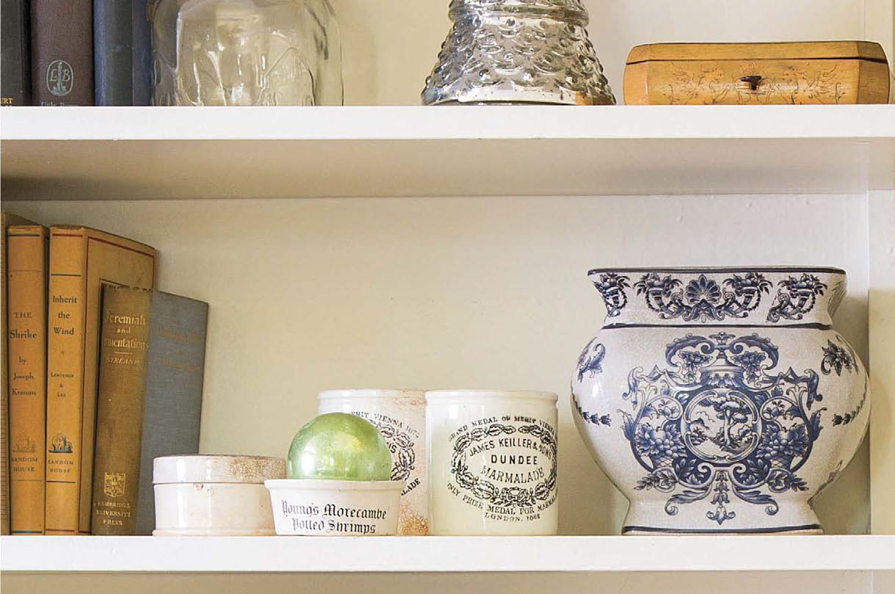 Keiller Dundee marmalade jars arranged on a shelving space alongside books and antique vases. 