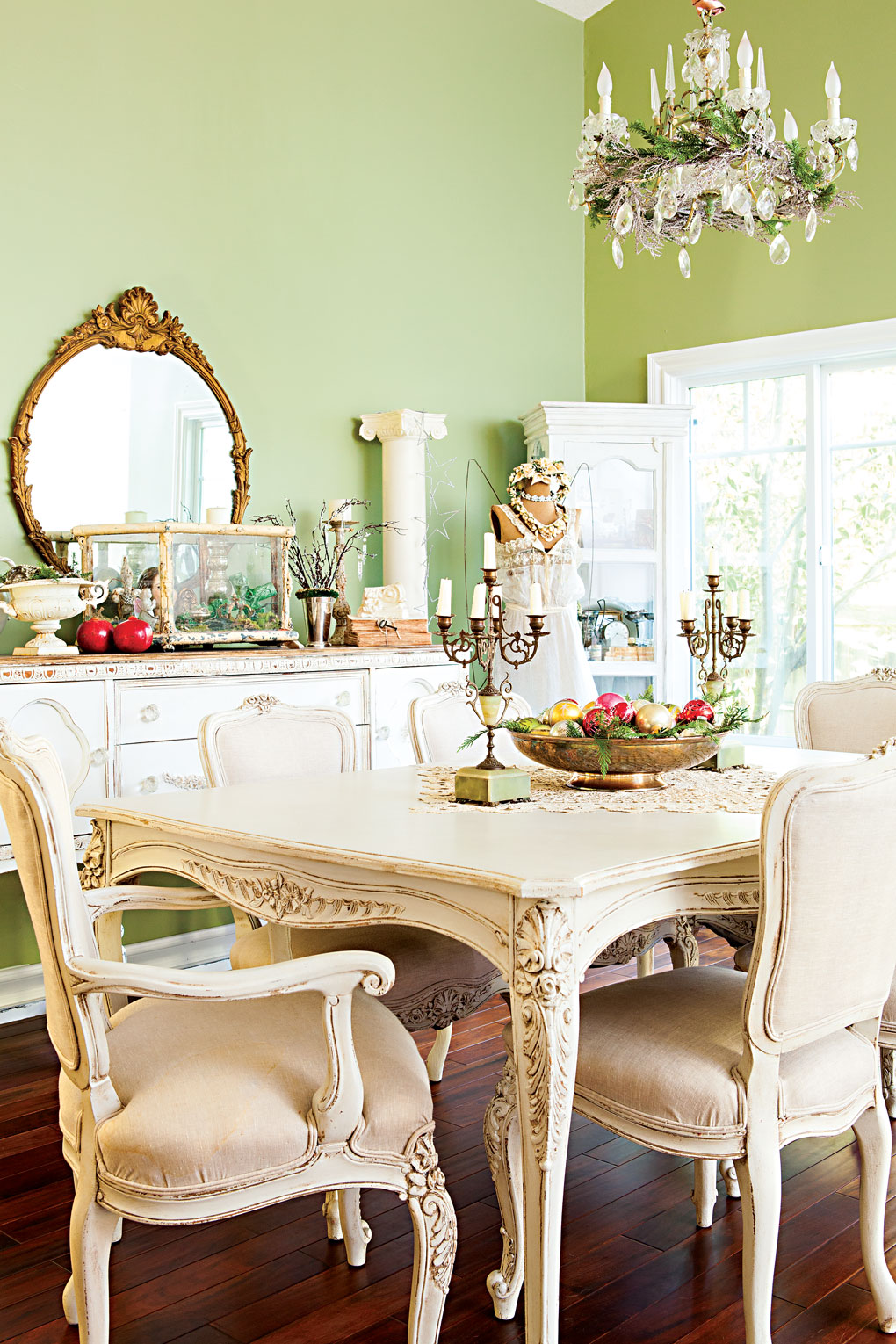 Light green walls surround a vintage white dining set with a hutch behind it. 